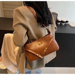 Borsa a spalla in pelle marrone stile Kelly indossata da modella in un caffè urbano