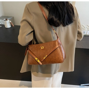 Dettaglio di borsa a mano vintage in pelle marrone con chiusura girevole dorata e finitura