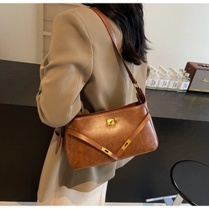 Borsa a tracolla retrò in pelle marrone indossata con un completo beige stile ufficio