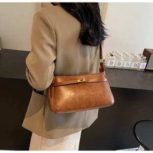 Borsa a tracolla marrone vintage con chiusura dorata indossata su un blazer beige