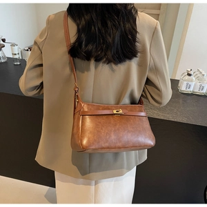 Modella che indossa una borsa a tracolla vintage marrone scuro con fibbia dorata al caffè