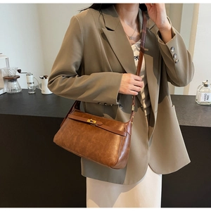 Dettaglio di borsa a tracolla vintage marrone con fibbia dorata, mostrata in un caffè accogliente