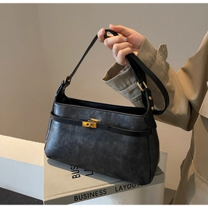 Dettaglio della borsa in pelle nera vintage con texture opaca e chiusura dorata