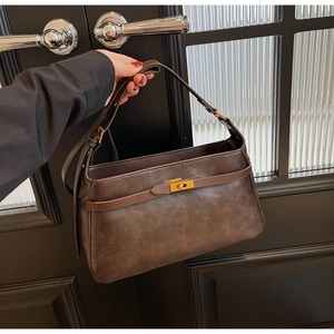 Dettaglio borsa vintage in pelle marrone con chiusura girevole dorata e texture opaca