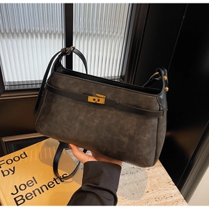 Dettaglio borsa in pelle scamosciata grigio scuro con cinturino nero e chiusura dorata