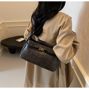 Dettaglio posteriore della borsa a spalla Kelly in pelle grigia indossata su un trench beige