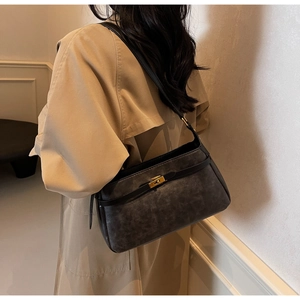 Dettaglio borsa a spalla retrò grigio scuro con chiusura dorata su trench beige