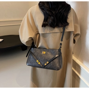 Vista laterale della borsa a tracolla in pelle grigio scuro vintage su trench coat beige