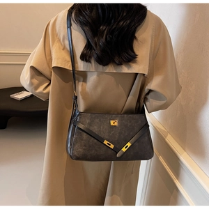 Dettaglio borsa a tracolla grigio opaco con fibbia dorata su outfit trench coat