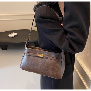 Dettaglio della borsa a tracolla in pelle marrone scuro vintage con fibbia dorata e design