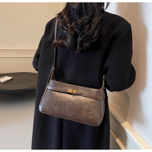 Dettaglio di una borsa a tracolla vintage in pelle marrone con chiusura girevole oro