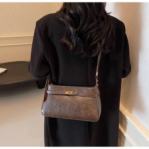 Dettaglio borsa a tracolla vintage marrone scuro con chiusura a rotazione dorata