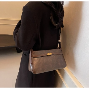Vista laterale di una borsa a tracolla vintage marrone scuro con fibbia dorata sul modello