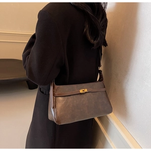 Dettaglio borsa a tracolla vintage marrone con chiusura girevole dorata e trama in ecopelle
