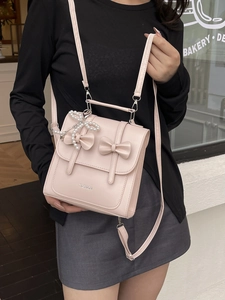 Sac bandoulière rose en similicuir avec nœuds décoratifs et pendentif en perles
