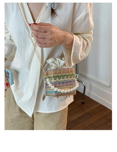 Detail of colorful woven crossbody bag with pearl handle and metal chain strap
