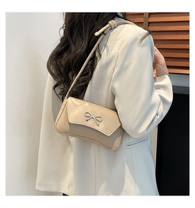 Dettaglio borsa a spalla in PU beige con fiocco in metallo argento e chiusura a patta