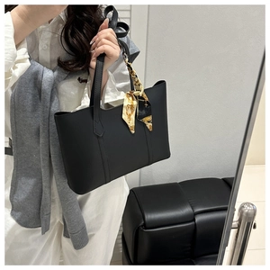 Detail of black tote bag with matte leather finish and elegant baroque printed silk scarf