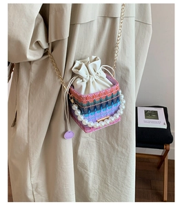 Detail of colorful woven bucket bag with pearl handle and golden chain strap