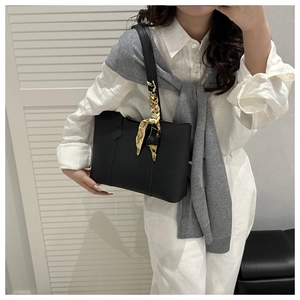 Black leather tote bag detail with stylish printed silk scarf wrapped around the handle