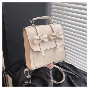 Détail du sac à dos en similicuir beige avec nœuds papillon et lettrage FASHION