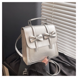 Détail du sac à dos papillon argenté avec texte de mode et texture en cuir brillant