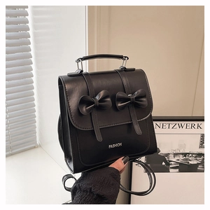 Detail of black PU leather backpack with two decorative bows and top handle