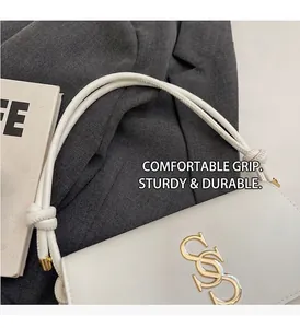 Detail van de witte lederen handtas met geknoopte handvatten en goudkleurig metalen logo