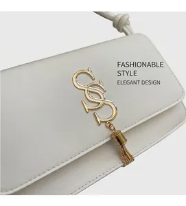 Detail van witte leren schoudertas met gouden hardware en elegante metalen kwastjes