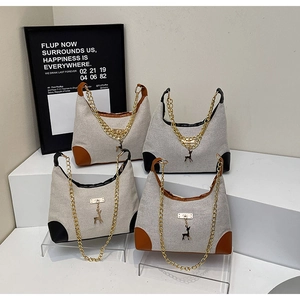 Detail of canvas tote bags with contrast leather corners and gold deer pendants