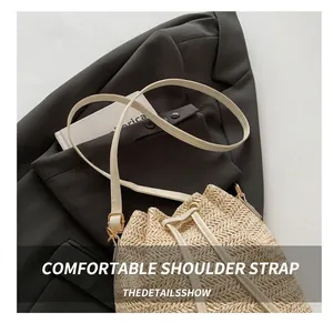 Détail de la bandoulière en cuir blanc réglable et boucle dorée sur un sac en paille