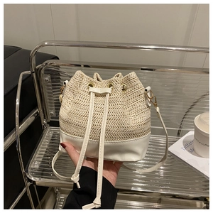 Détail du sac seau en paille blanc cassé avec fermeture à cordon et base en cuir blanc