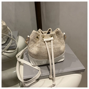 Détail du sac seau en paille tissée avec garniture en cuir blanc et cordon de serrage