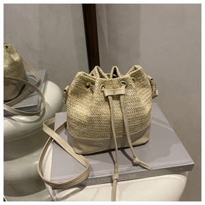 Détail du sac seau en paille tressée avec fond en cuir beige lisse et fermeture à cordon