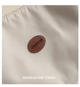 Close-up of beige nylon tote bag with stitched brown leather patch and Fashion logo