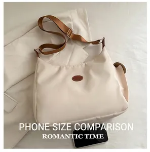 Close-up of a cream nylon tote bag with leather patch and brown adjustable shoulder strap