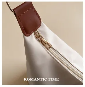 Close-up of a smooth gold zipper on a creamy nylon tote bag with leather accents