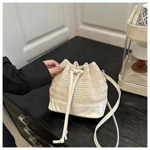 Détail du sac seau en paille tressée avec base en cuir et fermeture à cordon réglable