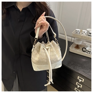 Détail du sac seau en paille tressée avec bordure en cuir et boucles métalliques
