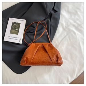 Close-up of caramel woven texture handbag with delicate pleats and slim shoulder strap