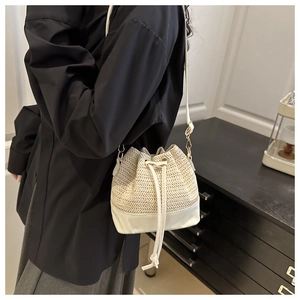 Détail du sac seau en paille tressée avec base en cuir et cordon porté par un mannequin