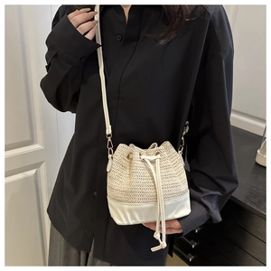 Détail du sac seau en paille avec cordon en cuir blanc et attaches métalliques