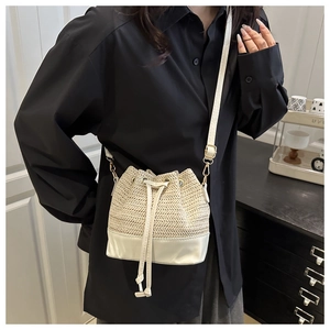Détail du sac seau en paille tissée avec base en cuir blanc et cordon réglable