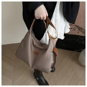 Macro shot of brown nylon tote bag with leather FASHION patch and crossbody strap
