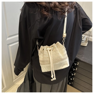 Détail du sac seau en paille et cuir blanc avec fermeture à cordon et boucles dorées