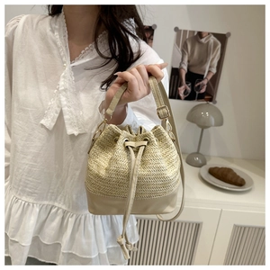Détails du sac seau en paille beige avec base en cuir et cordon de serrage