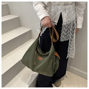 Detail view of the green nylon shoulder bag with a brown fashion logo and textured strap