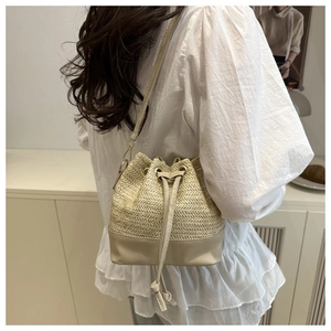 Détail du sac seau en paille et cuir avec fermeture à cordon et bandoulière