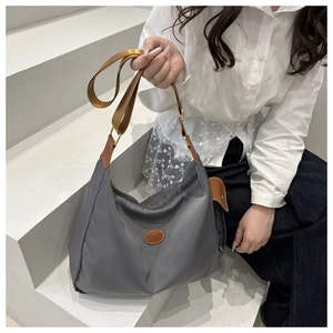 Close-up of grey nylon tote bag with brown fashion leather patch and durable strap