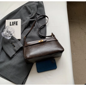 Dettaglio borsa in pelle vintage marrone scuro con fibbia dorata e smartphone per scala